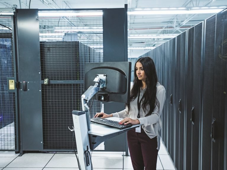 Mixed race technician using computer in server room