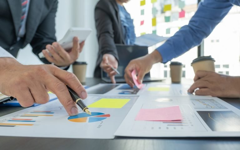 Hand,Holding,Pen,,Businesswomen,And,Businessmen,Team,Meeting,To,Plan